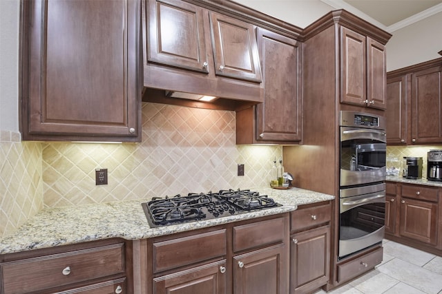 kitchen with light stone counters, decorative backsplash, crown molding, stainless steel double oven, and black gas cooktop