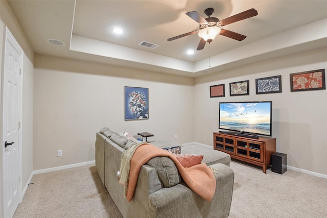 living room featuring visible vents, a raised ceiling, ceiling fan, and light colored carpet