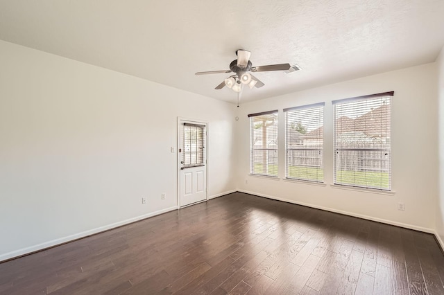 spare room with a ceiling fan, baseboards, dark wood finished floors, and visible vents