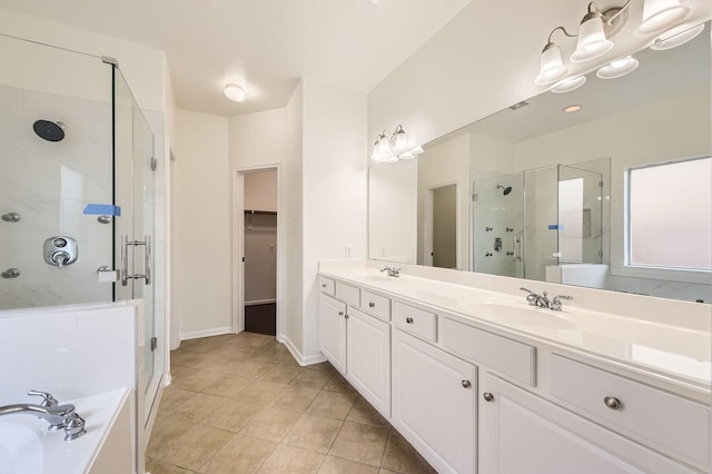 bathroom featuring double vanity, a garden tub, a shower stall, a sink, and a spacious closet