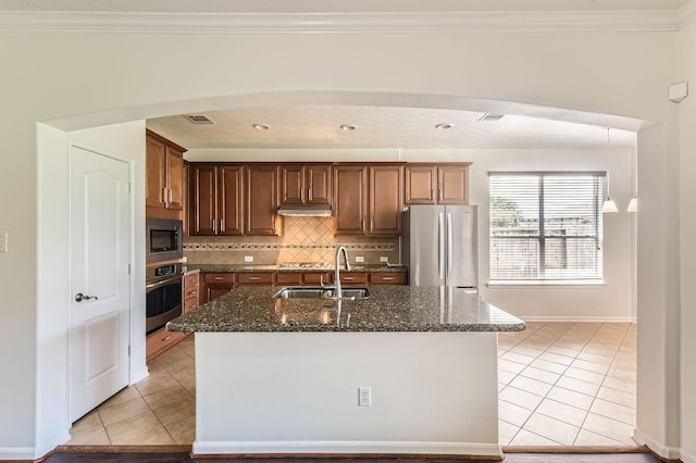 kitchen featuring a sink, appliances with stainless steel finishes, dark stone countertops, and light tile patterned flooring