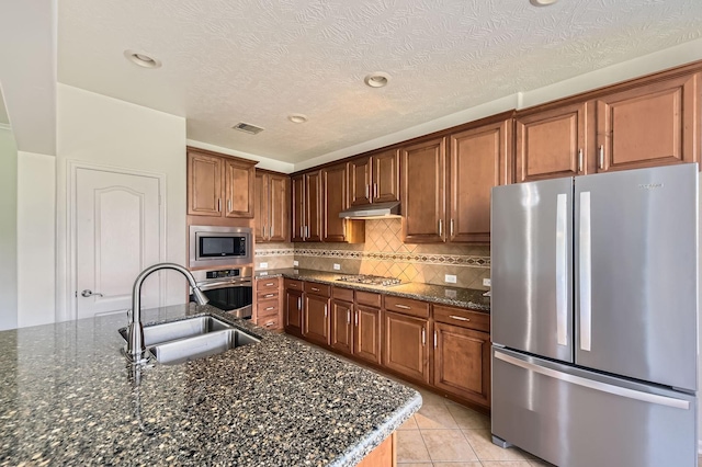 kitchen featuring visible vents, tasteful backsplash, a sink, dark stone countertops, and appliances with stainless steel finishes