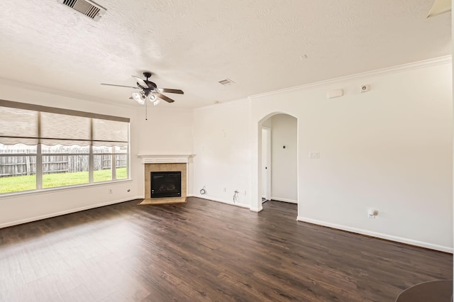 unfurnished living room featuring visible vents, ornamental molding, ceiling fan, dark wood-type flooring, and arched walkways