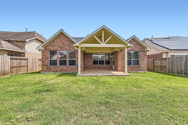 back of house featuring a fenced backyard, a patio, a yard, and brick siding