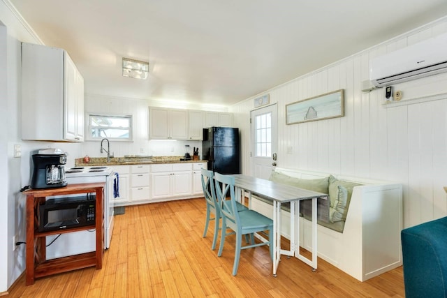 4006 Reeves Dr, Galveston, TX 77554 - kitchen featuring black appliances, a wall mounted AC, white cabinetry, and healthy amount of natural light