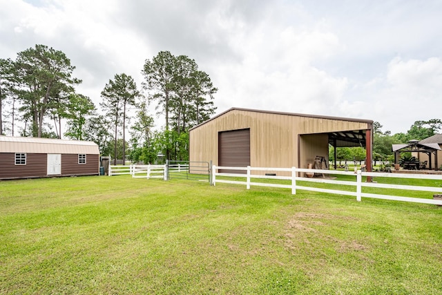 exterior space with fence, a pole building, a gazebo, a detached garage, and an outbuilding