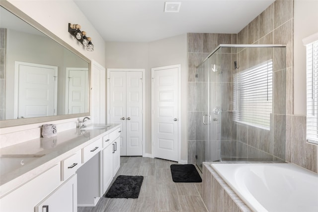 bathroom with double vanity, a garden tub, visible vents, and a stall shower