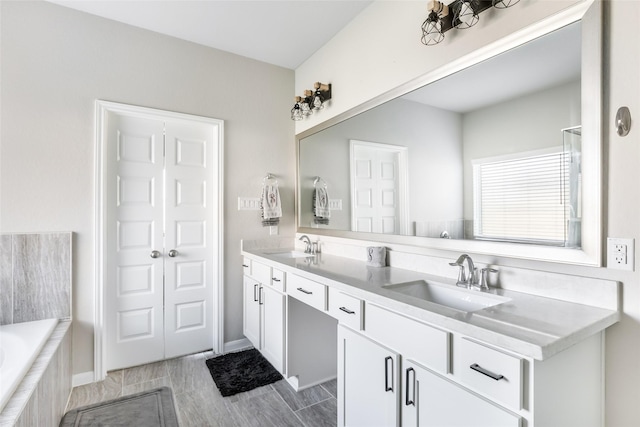 bathroom featuring double vanity, a sink, and a relaxing tiled tub