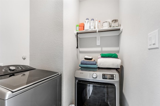 laundry room featuring washer and dryer, a textured wall, and laundry area