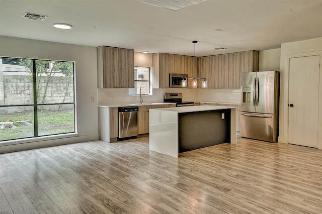 15626 Whitewater Ln, Houston, TX 77079 - kitchen featuring a kitchen island, modern cabinets, light countertops, appliances with stainless steel finishes, and backsplash