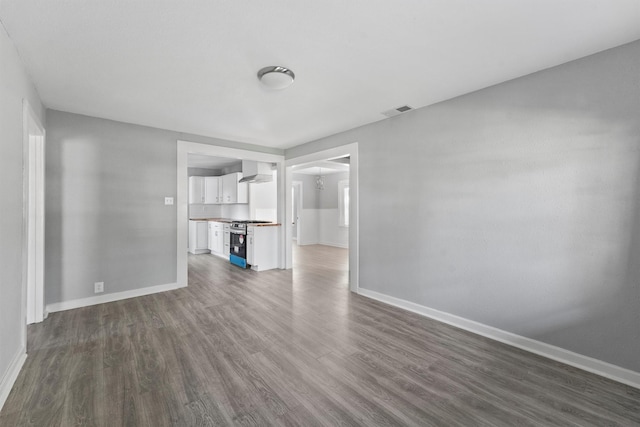 unfurnished living room featuring baseboards, visible vents, and dark wood-type flooring