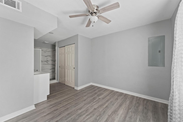 unfurnished bedroom with wood finished floors, visible vents, electric panel, and baseboards