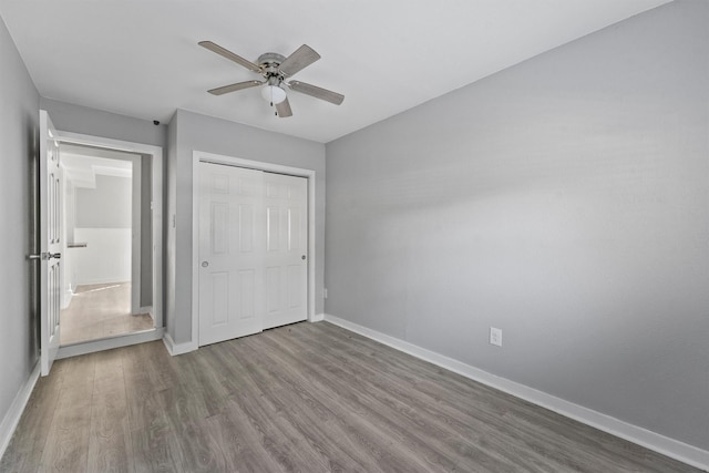 unfurnished bedroom with a closet, ceiling fan, wood finished floors, and baseboards