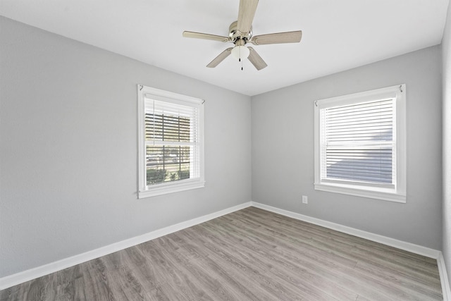 spare room featuring wood finished floors, a ceiling fan, and baseboards