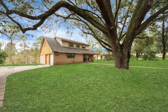 view of side of property featuring driveway, a yard, a garage, and brick siding