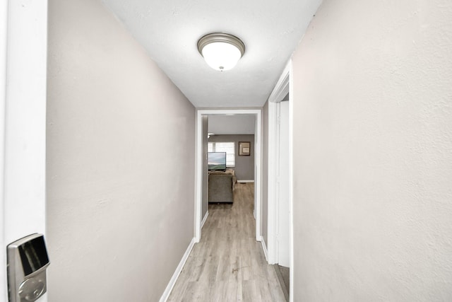 corridor with light wood finished floors and baseboards