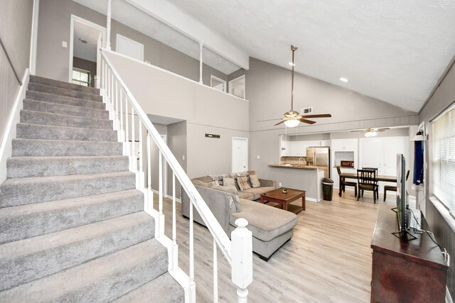 living area featuring ceiling fan, stairway, high vaulted ceiling, and light wood-style floors