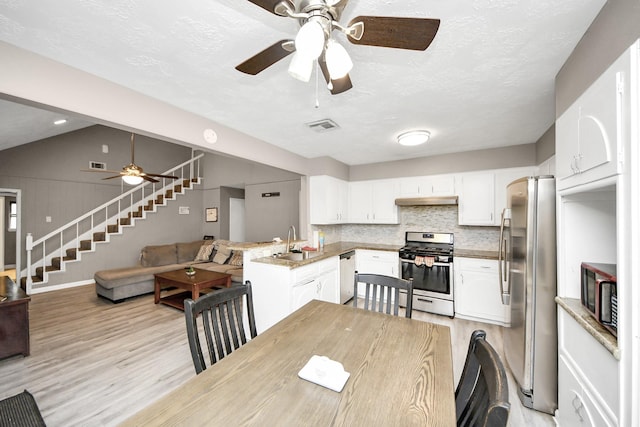 dining room featuring stairway, visible vents, light wood-type flooring, and a ceiling fan