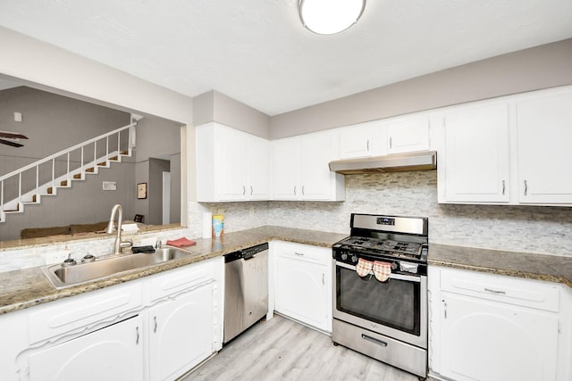 kitchen featuring stainless steel appliances, under cabinet range hood, white cabinets, a sink, and light wood-type flooring