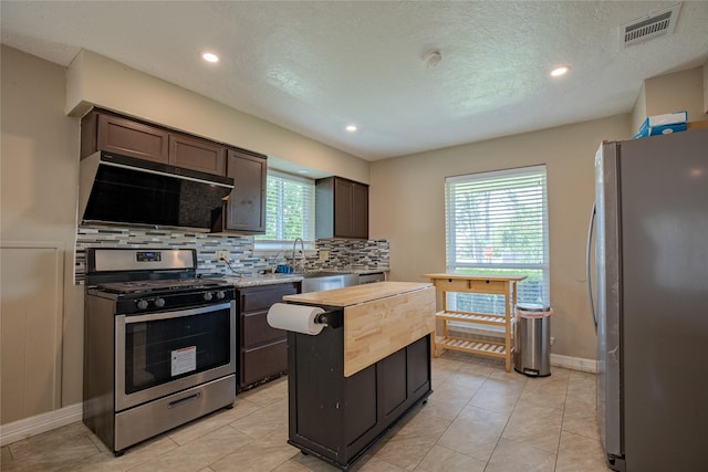 kitchen featuring a sink, stainless steel appliances, tasteful backsplash, visible vents, and ventilation hood