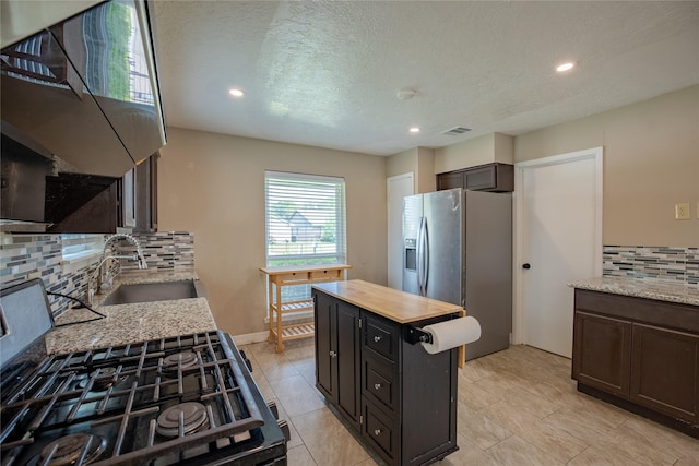 kitchen with recessed lighting, a sink, stainless steel fridge, tasteful backsplash, and visible vents