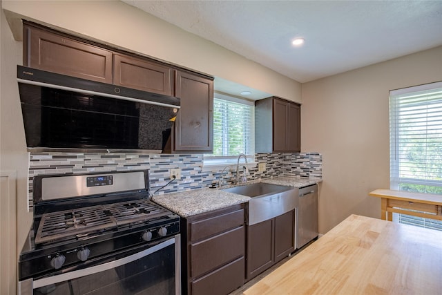 kitchen with dark brown cabinetry, recessed lighting, stainless steel appliances, backsplash, and a sink