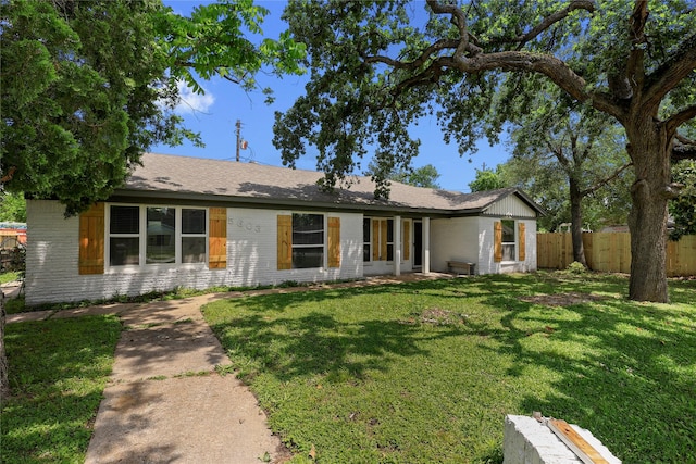 ranch-style home with brick siding, fence, and a front lawn