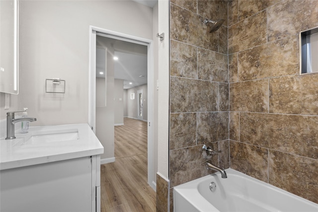 full bath with wood finished floors, vanity, bathtub / shower combination, and baseboards