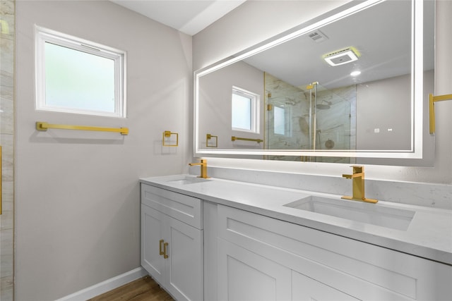 full bathroom with a marble finish shower, a sink, double vanity, and baseboards