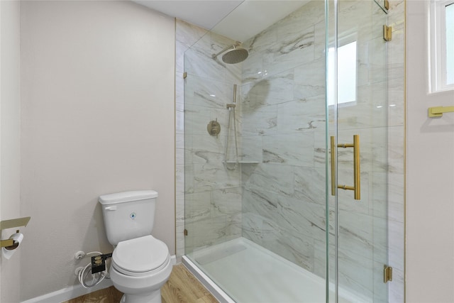 full bathroom featuring baseboards, wood finished floors, a shower stall, and toilet