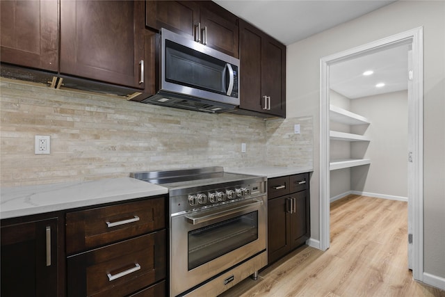 5603 Hilary St, Houston, TX 77026 - kitchen with dark brown cabinetry, light wood finished floors, backsplash, baseboards, and appliances with stainless steel finishes
