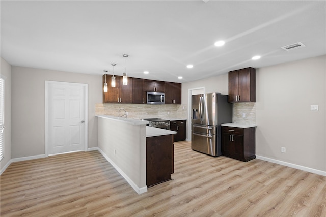 kitchen with dark brown cabinetry, light wood-style flooring, stainless steel appliances, light countertops, and a peninsula