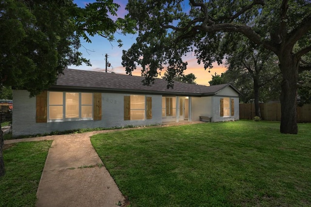 5603 Hilary St, Houston, TX 77026 - back of property at dusk with a yard, roof with shingles, and fence