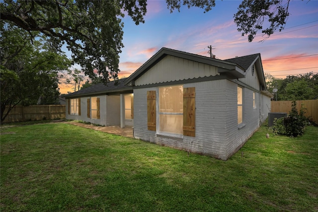 5603 Hilary St, Houston, TX 77026 - view of home's exterior with a fenced backyard, brick siding, a yard, and central AC unit