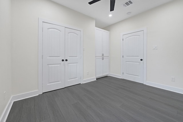 unfurnished bedroom featuring a ceiling fan, baseboards, dark wood-type flooring, visible vents, and a closet
