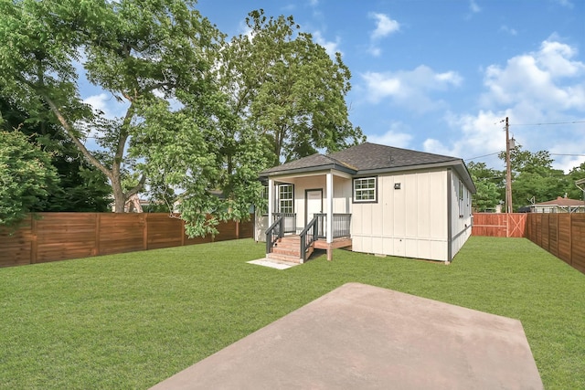 rear view of property featuring a yard, roof with shingles, a fenced backyard, and a patio area