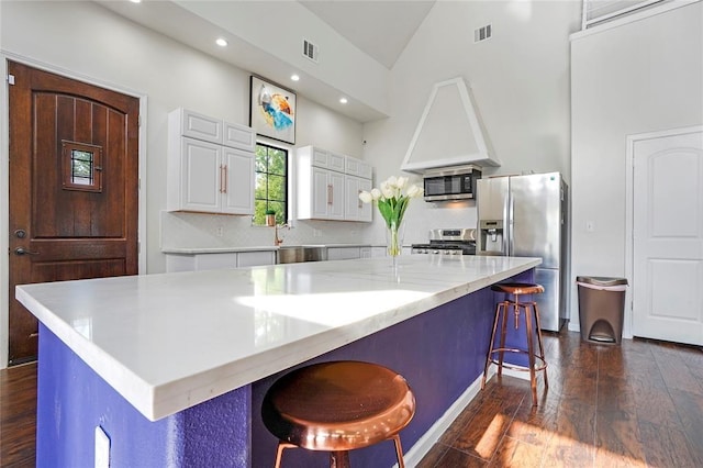 11215 Duane St, Houston, TX 77047 - kitchen with white cabinets, visible vents, stainless steel appliances, a kitchen bar, and dark wood-type flooring