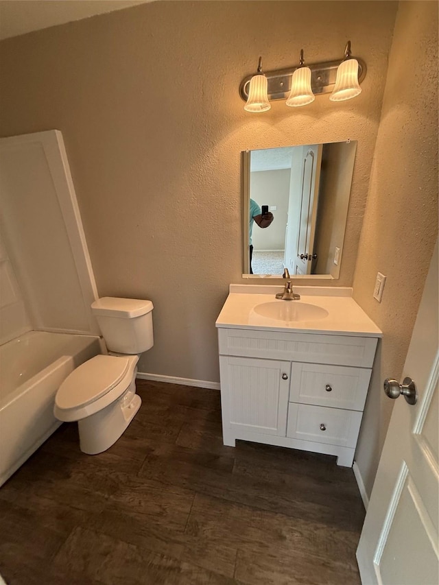full bath with toilet, vanity, wood finished floors, and baseboards