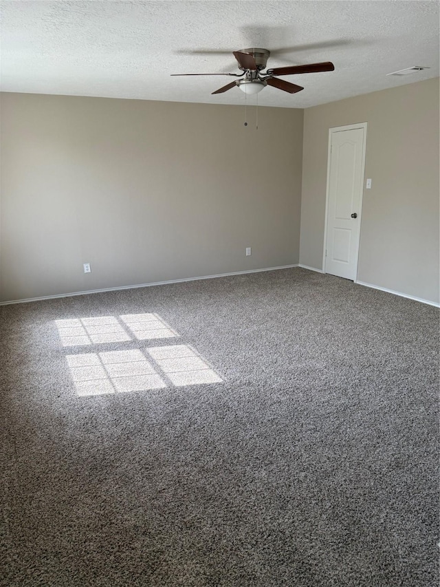 carpeted spare room featuring a textured ceiling, visible vents, a ceiling fan, and baseboards