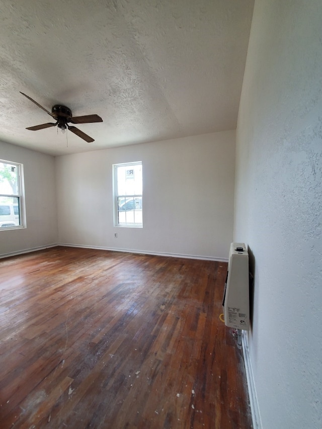 spare room with baseboards, ceiling fan, a textured ceiling, and wood-type flooring