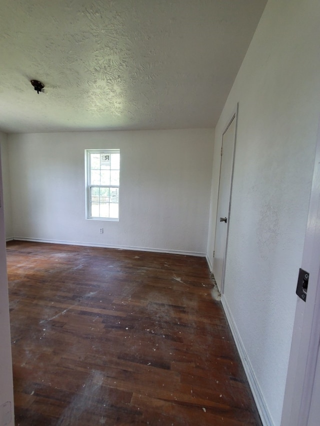 spare room featuring hardwood / wood-style floors, baseboards, and a textured ceiling