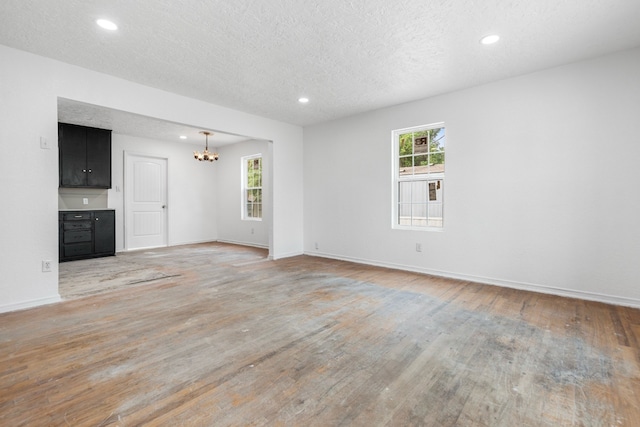 unfurnished room featuring recessed lighting, a notable chandelier, a healthy amount of sunlight, and light wood-type flooring