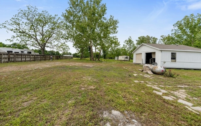 view of yard featuring an outbuilding, a detached garage, and fence
