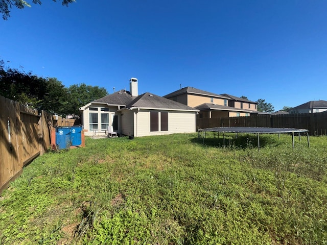 4326 Sunlit Pass Loop, Humble, TX 77396 - rear view of house with a lawn, a chimney, a fenced backyard, and a trampoline