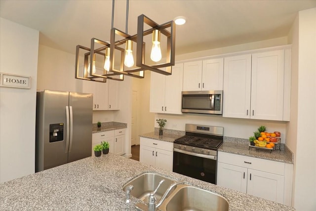 kitchen featuring an inviting chandelier, stainless steel appliances, decorative light fixtures, a sink, and white cabinetry