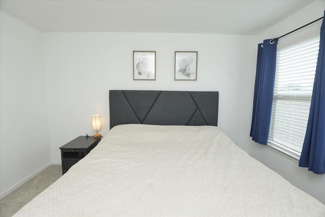 bedroom with light colored carpet and baseboards