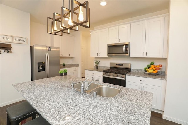 kitchen with white cabinetry, a sink, stainless steel appliances, a kitchen island with sink, and a notable chandelier