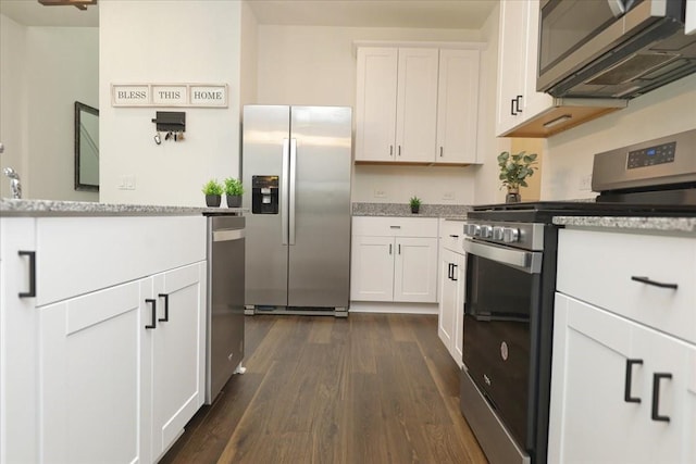 kitchen featuring appliances with stainless steel finishes, white cabinetry, light stone counters, and dark wood-style floors