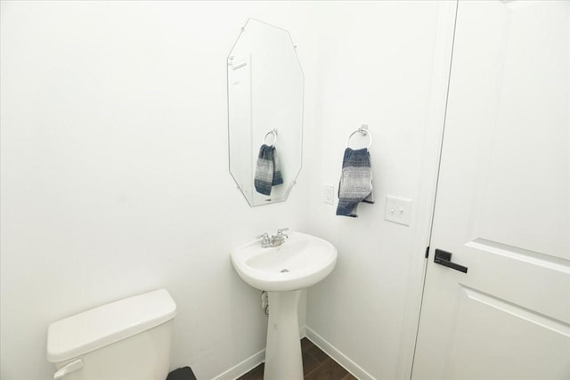 half bathroom with wood finished floors, toilet, and baseboards