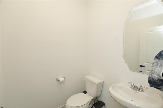half bathroom featuring toilet, a sink, and baseboards